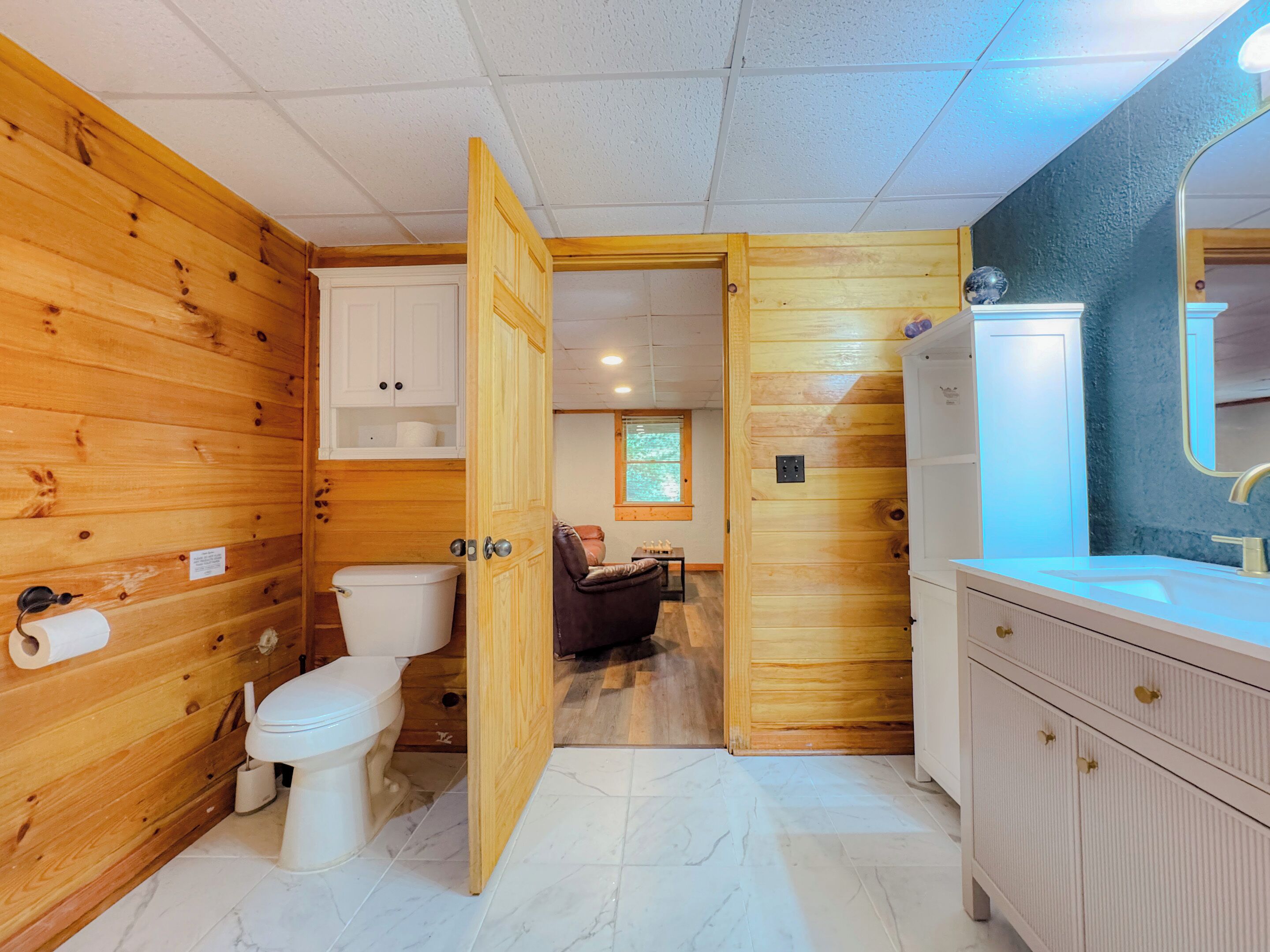 A wooden interior with a toilet, a cabinet, and a bathroom vanity.