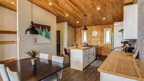 Une cuisine moderne avec des éléments en bois, un îlot central et des luminaires suspendus.