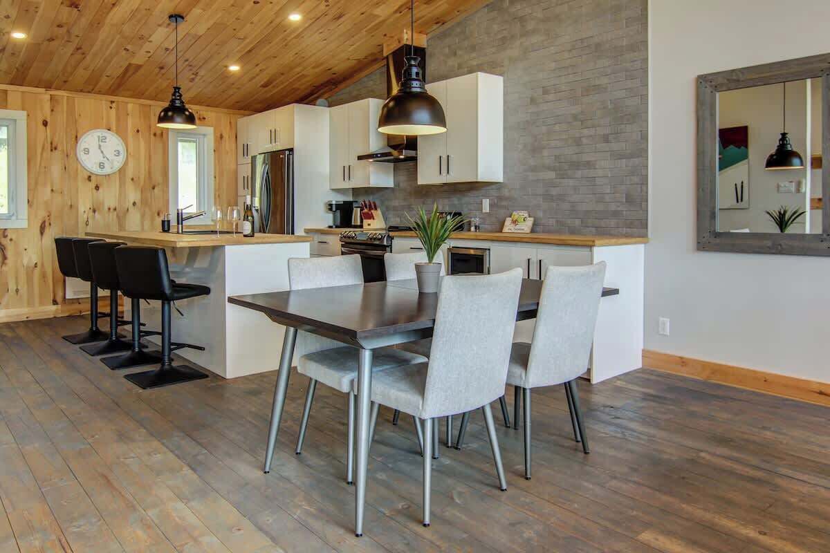 Une cuisine moderne avec des meubles en bois, un îlot central et un coin repas avec des chaises.