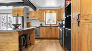 Une cuisine moderne avec des armoires en bois, des appareils électroménagers en acier inoxydable et une grande fenêtre.