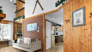 Un salon moderne avec un mur d’accent en briques, un ventilateur de plafond et un canapé confortable.