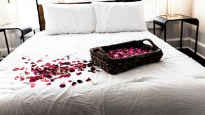 A bed with white bedding, a basket of pink flowers, and scattered petals. - Quaint 3BR - Minutes to Downtown San Angelo - Sleeps 6 (San Angelo)