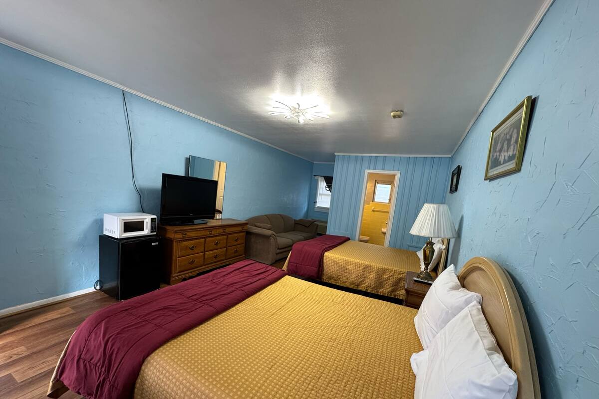 A hotel room with two beds, a TV, a dresser, and a microwave.