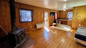 L’intérieur d’un chalet en bois comprend une cheminée, un coin repas et une cuisine.