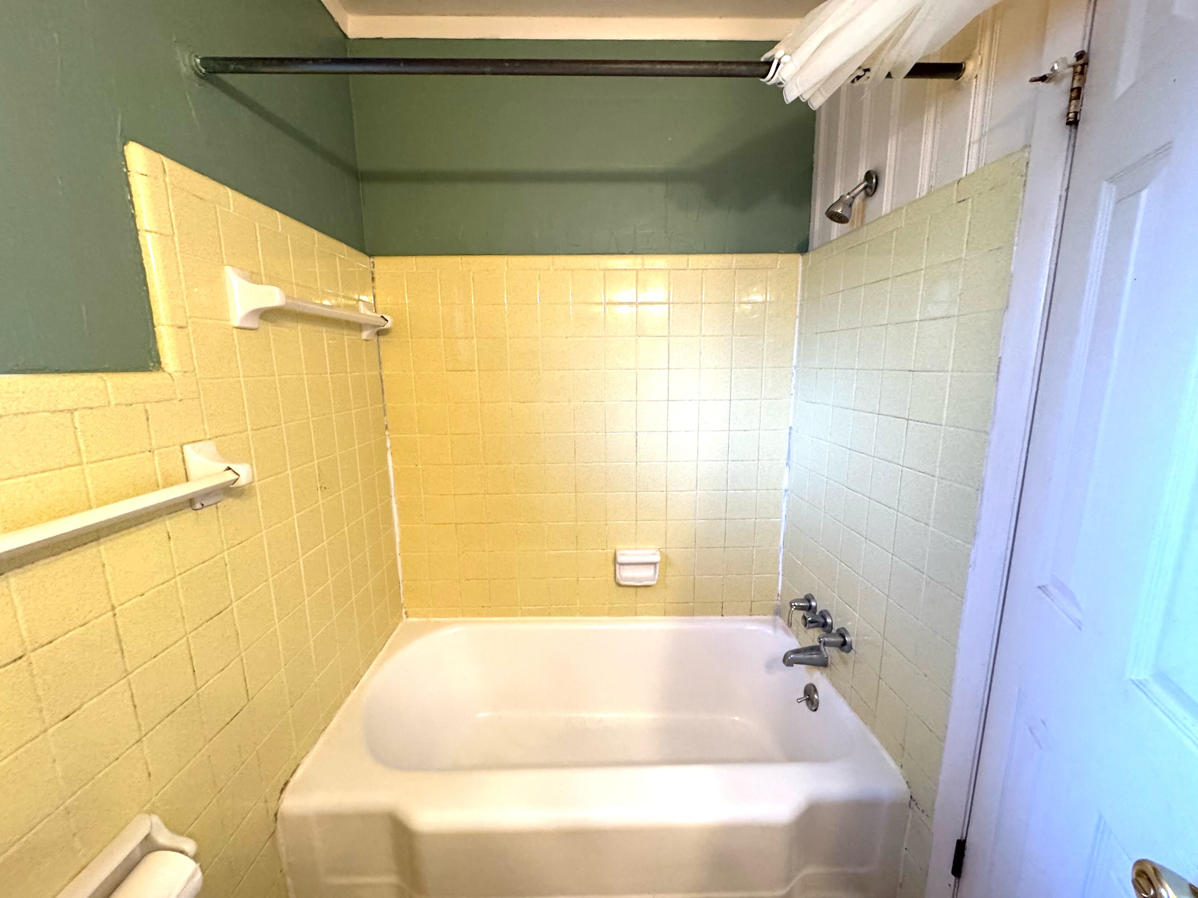 A bathroom with a bathtub, a towel rack, and a toilet.
