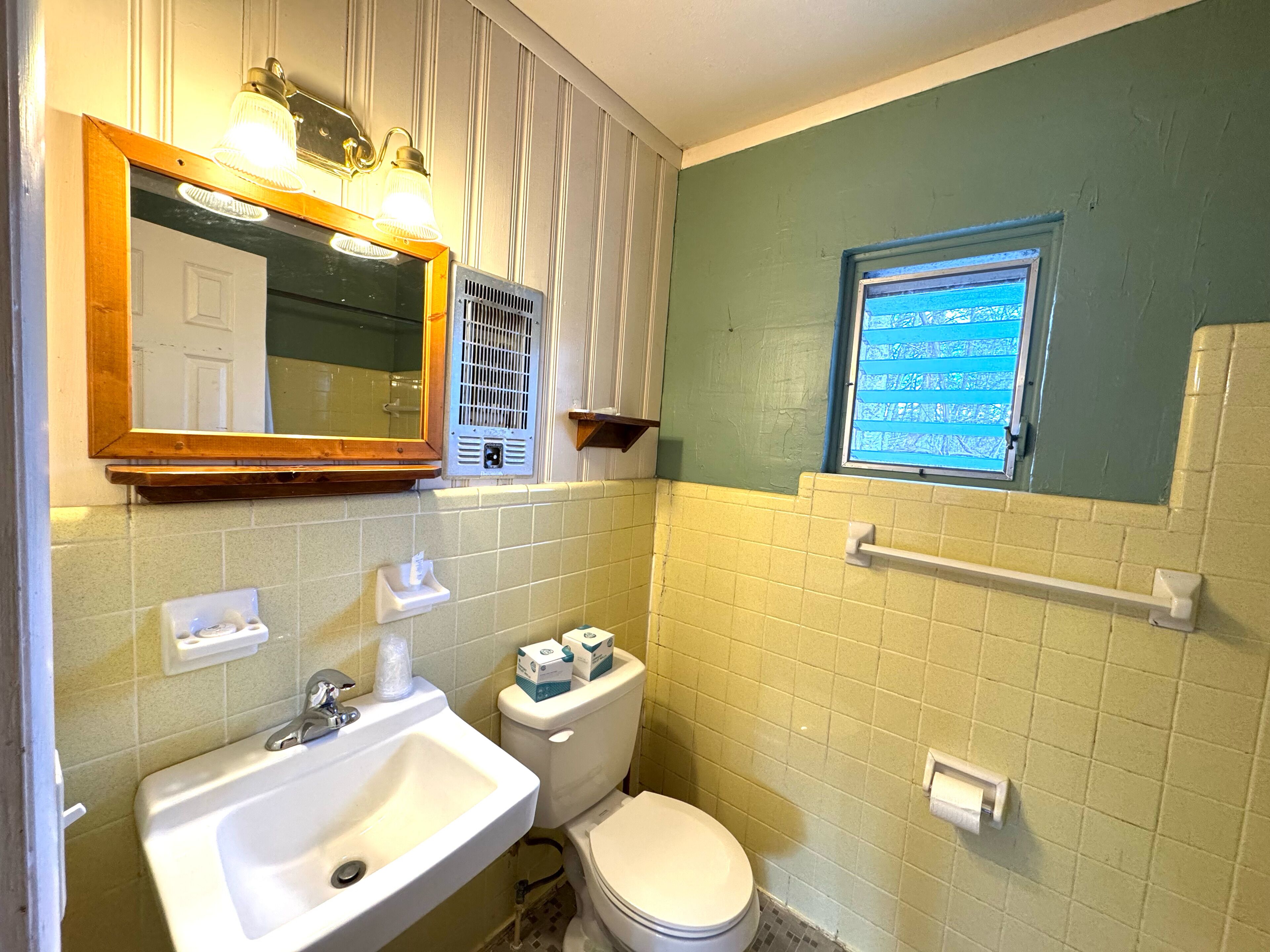 Une salle de bain avec un lavabo, des toilettes et un miroir.