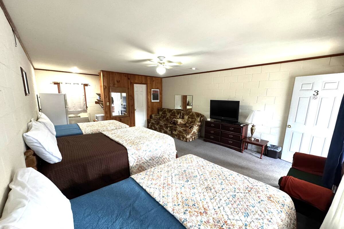 A room with two beds, a television, a dresser, and a door with the number 3.