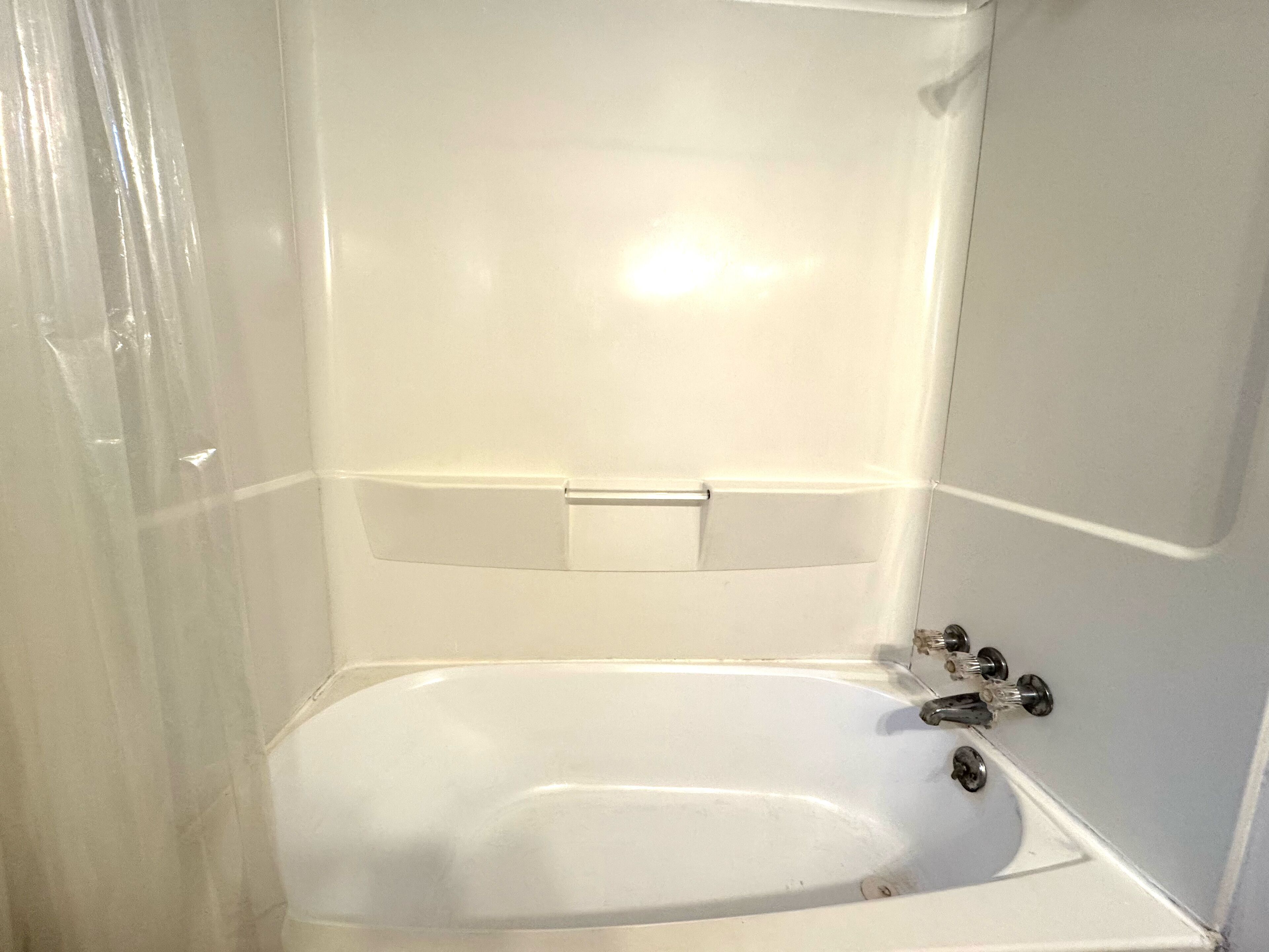 A white bathtub with a faucet and a control panel.