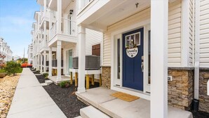 A row of white townhouses with blue doors, each featuring a small porch and a stone accent wall.