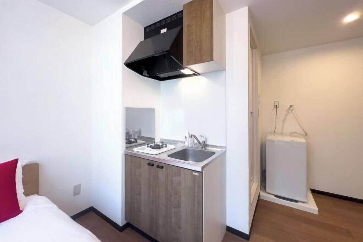 A compact kitchenette with a stove, sink, and storage cabinets.