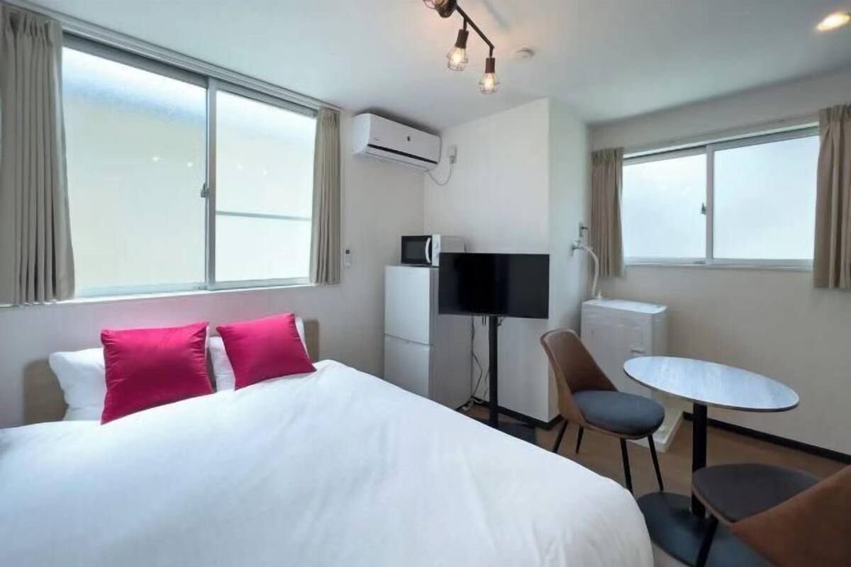A hotel room with a bed, a TV, a desk, and a chair.