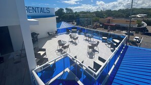 A rooftop patio with outdoor seating and a sign for "RENTALS". - Charming studio in the Heart of Sosua, Facing the pool & at 2 min from the Beach (Sosúa)