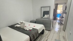 A hotel room with a bed, a dresser, a mirror, and a small table. - Charming studio in the Heart of Sosua, Facing the pool & at 2 min from the Beach (Sosúa)