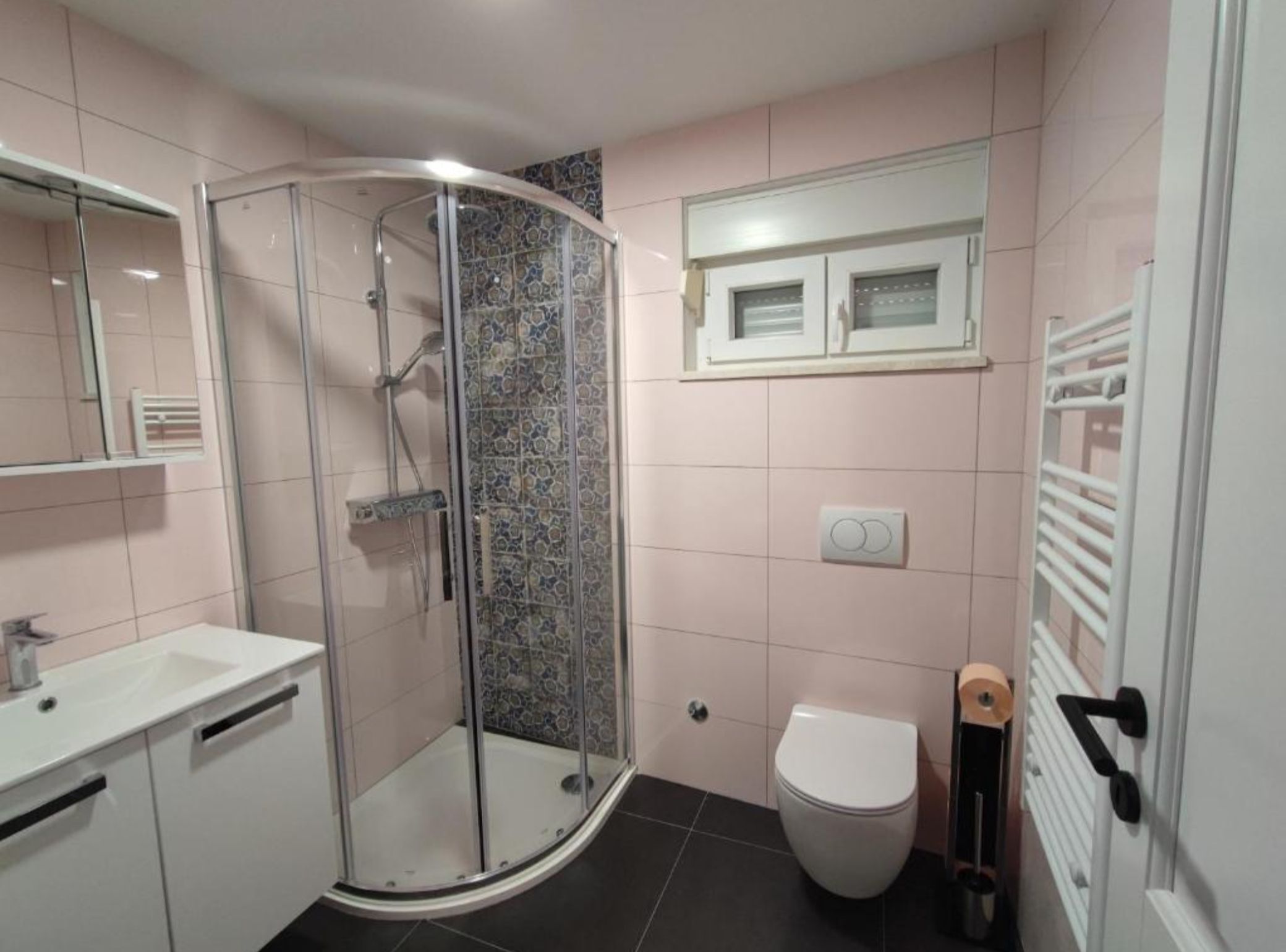 A bathroom with a glass-enclosed shower, a toilet, a sink, and a mirror.