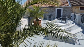 Une terrasse sur le toit, avec un mur en pierre, un pot de fleurs et du mobilier d’extérieur.