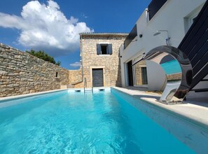 A swimming pool with stone walls, a stone building, and a modern house with a large window. - Villa Galant With Pool & Sauna Maružini (Kanfanar)