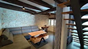 Un intérieur rustique avec des murs en pierre apparentes, un plafond en bois et un canapé moderne.