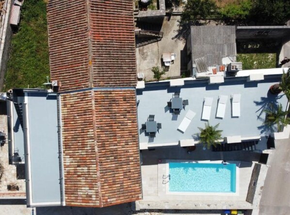Une terrasse sur le toit avec une piscine, des chaises longues et une structure en briques.