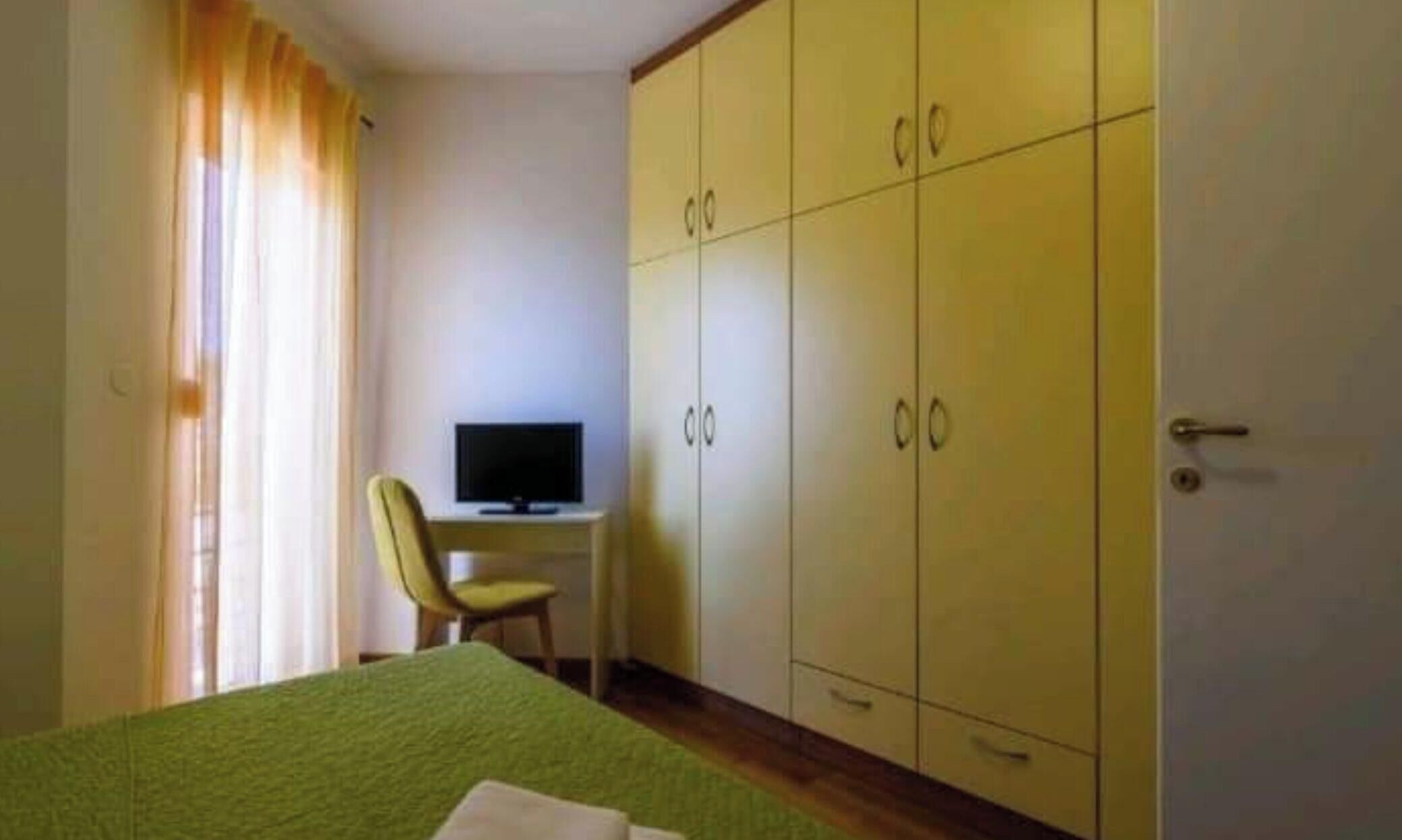 Une chambre d’hôtel avec un lit, un téléviseur posé sur un bureau et une armoire.