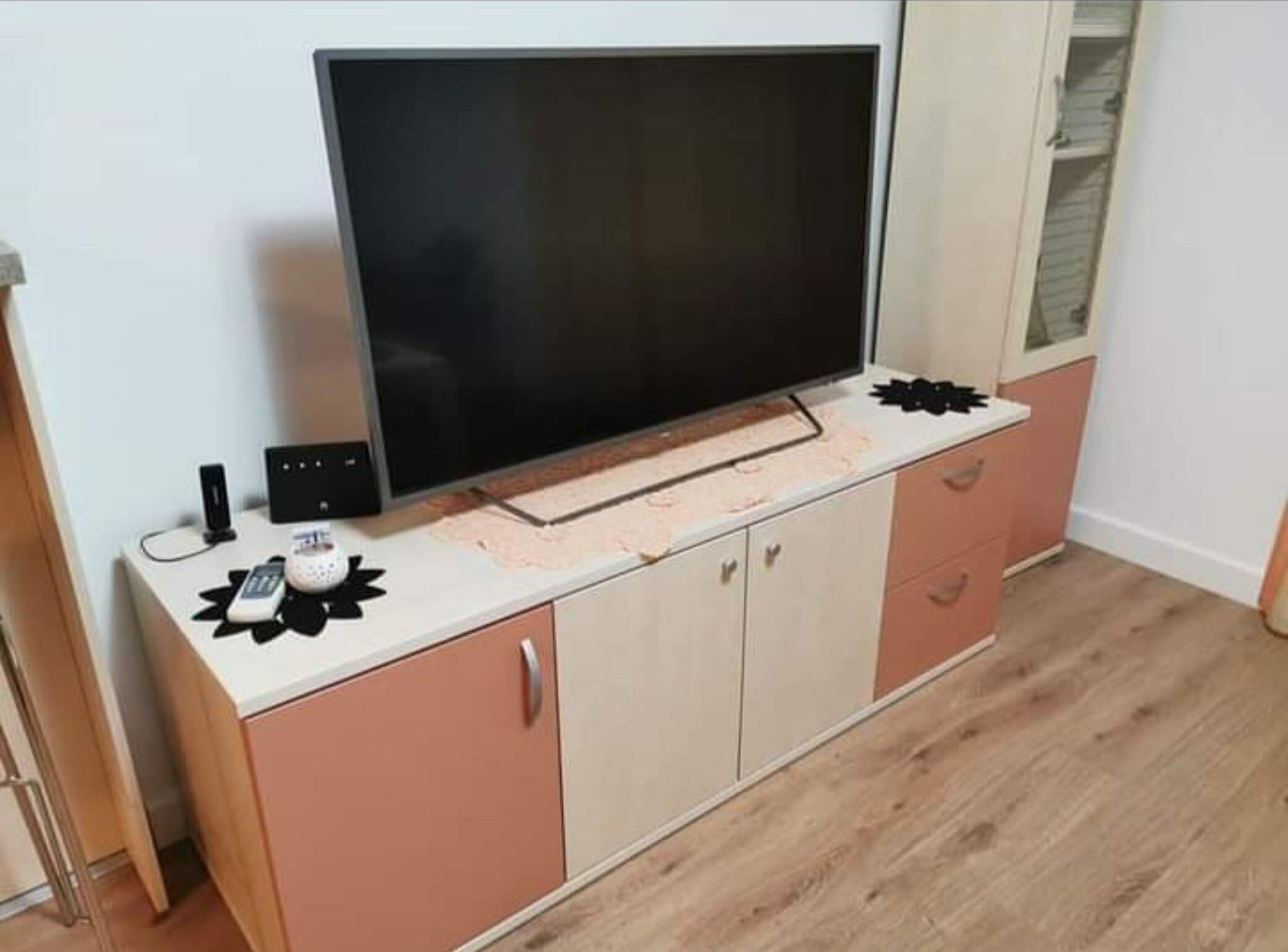 A TV on a cabinet with a remote and a speaker.