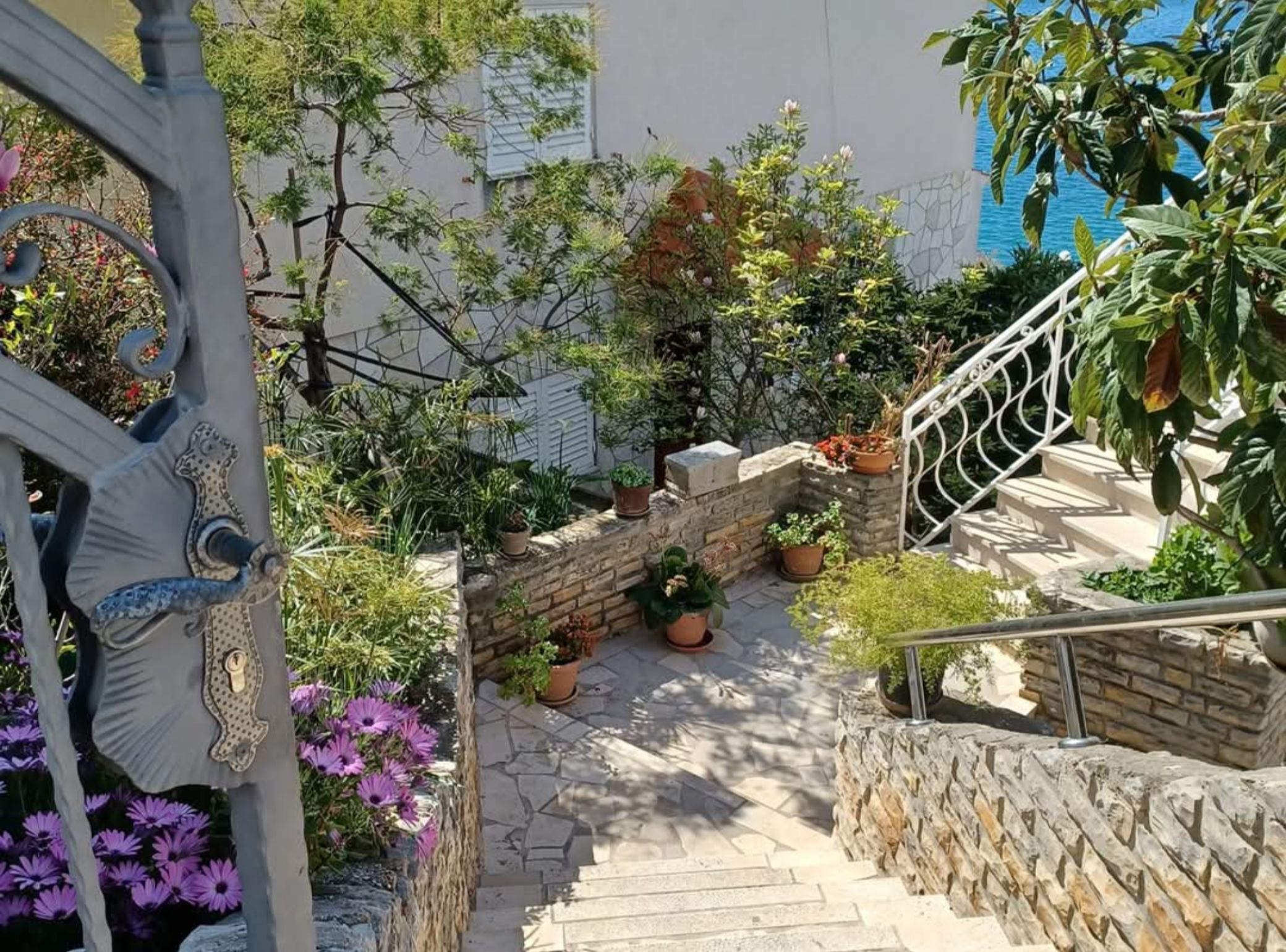 A stone staircase leading to a balcony with potted plants and flowers.