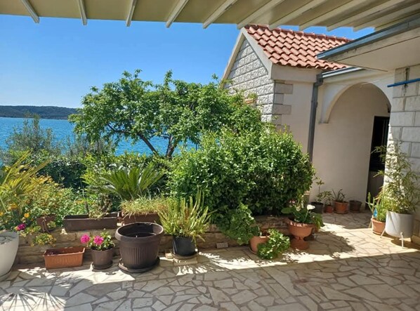 A covered patio with potted plants and a view of the sea. - Apartments Bilić Trogir (Trogir)