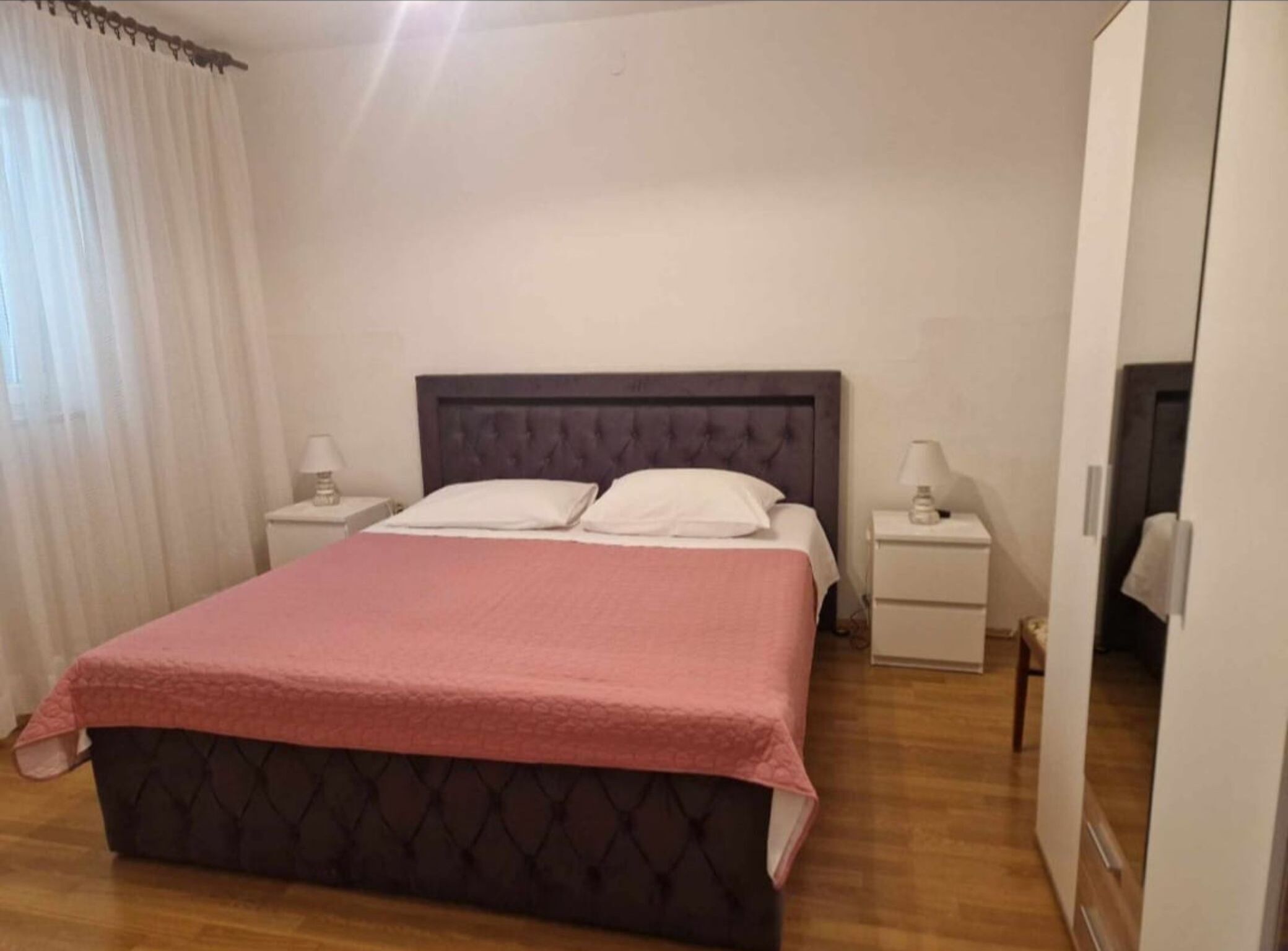 Une chambre à coucher avec un grand lit, deux tables de chevet et une porte.