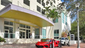 A hotel entrance with a red sports car parked in front, a covered walkway, and a sign for 'Hotel Arya'. - SF Modern Comfort Steps from the Ocean Breeze (Miami)