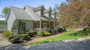 A two-story house with a front porch, a stone foundation, and a metal roof.
