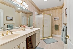 A bathroom with a double sink, a large mirror, a walk-in shower, and a towel rack.