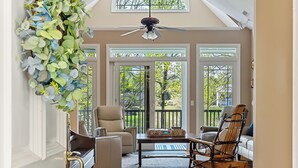 A spacious living room with a piano, two chairs, a coffee table, and a decorative wreath.