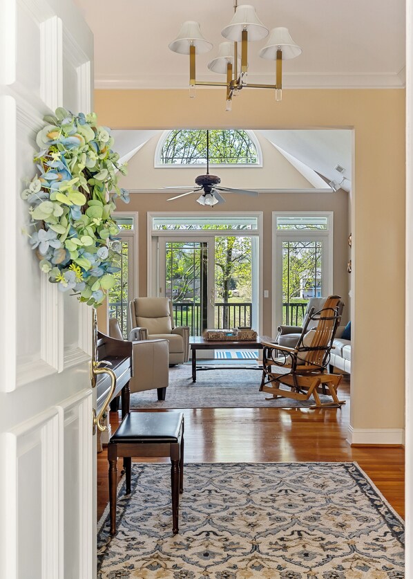 A spacious living room with a piano, two chairs, a coffee table, and a decorative wreath.