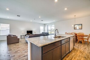 Une cuisine moderne dotée d’un plan de travail en granit, de meubles en bois et d’un coin repas avec des chaises en bois.