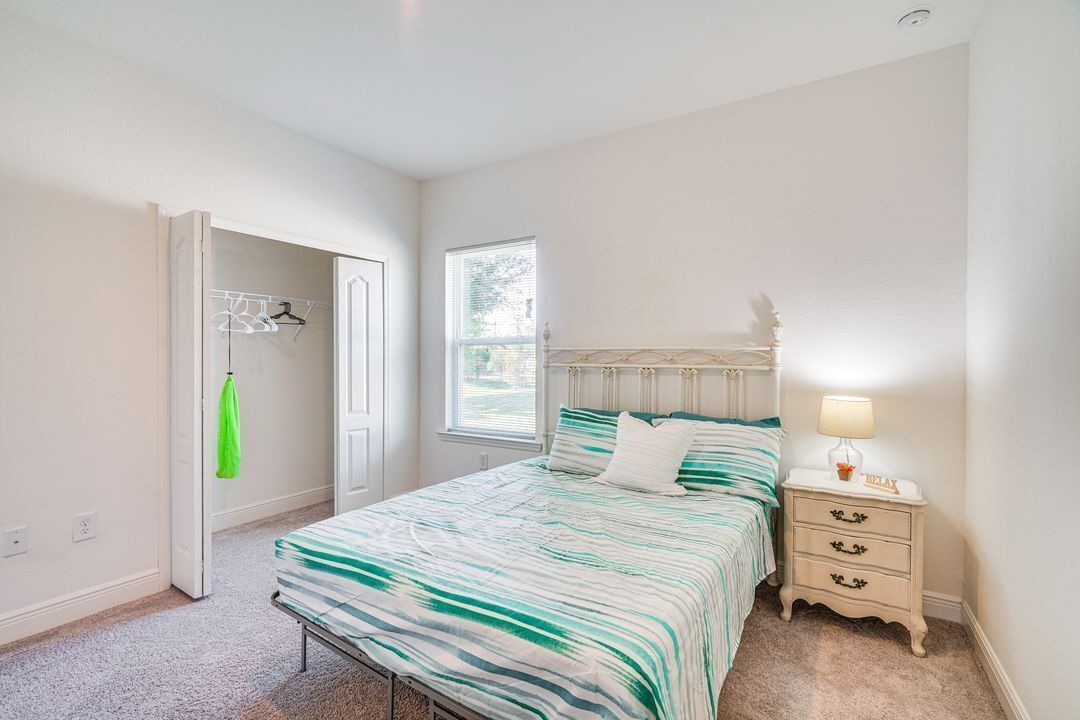 A bedroom with a bed, a nightstand, a window, and a door.