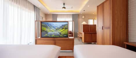 Une chambre d’hôtel avec deux lits, une télévision, des meubles en bois et une vue sur la montagne.