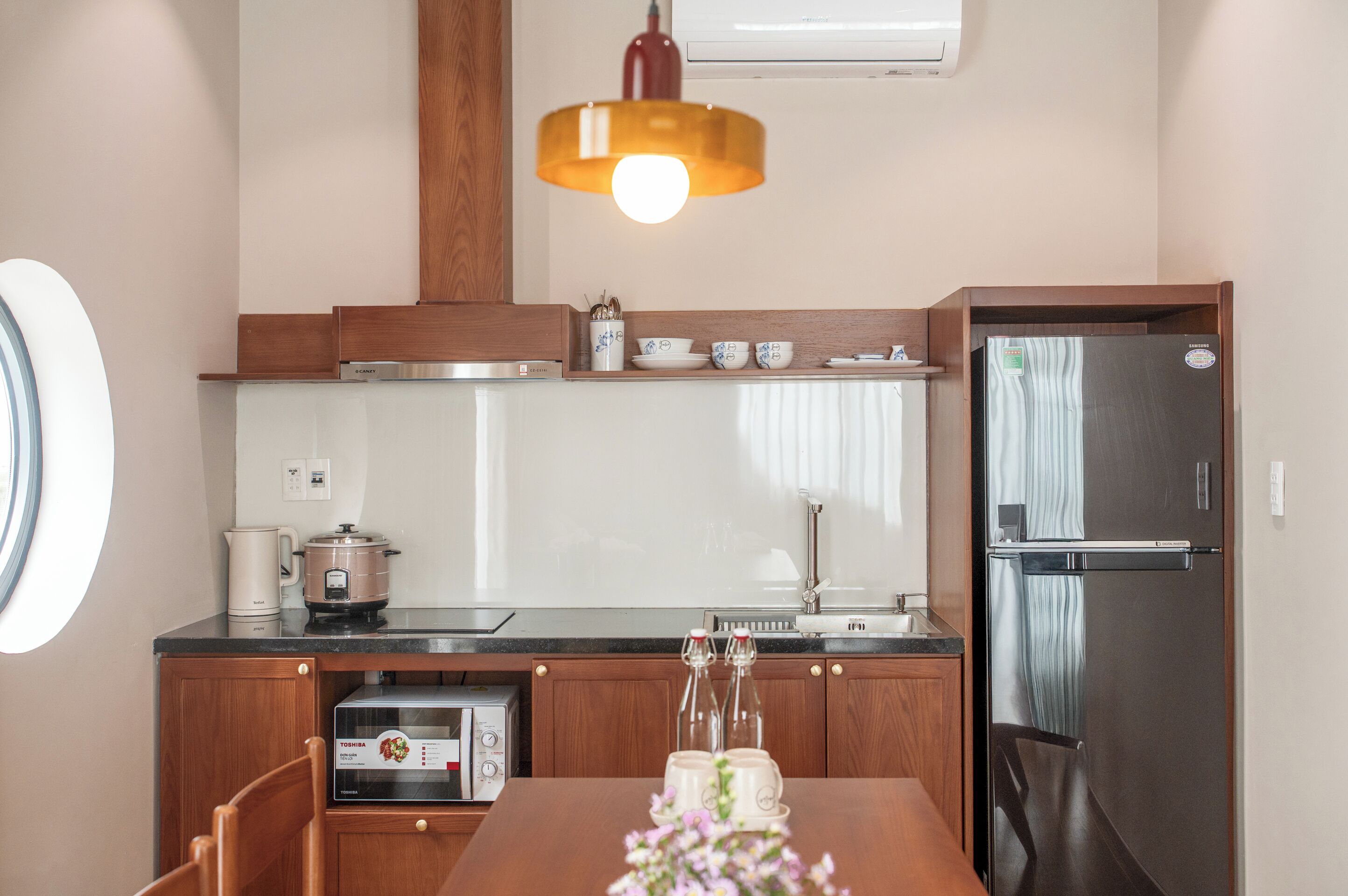 Une cuisine moderne équipée d’un four encastré, d’un réfrigérateur, d’un évier et d’un coin repas avec une table et des chaises.