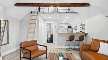 Ein modernes Wohnzimmer mit einer offenen Decke im Loft-Stil, einer Küchenzeile und einem sichtbaren Badezimmer.