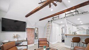 A modern living room with a fireplace, leather chairs, a coffee table, and a kitchen area visible in the background. - Unique BOHO Ohio City Loft Apt (Cleveland)