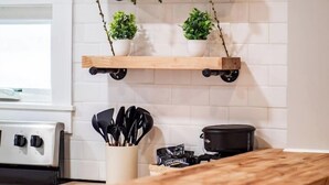 A kitchen with white tiled walls, a wooden countertop, and two wooden shelves with potted plants. - Unique BOHO Ohio City Loft Apt (Cleveland)