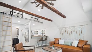 A modern living room with a brown leather sofa, a coffee table, and a wooden ladder against the wall. - Unique BOHO Ohio City Loft Apt (Cleveland)