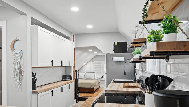 A modern kitchen with white cabinets, a wooden countertop, and a built-in stove. - Unique BOHO Ohio City Loft Apt (Cleveland)