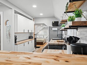 A modern kitchen with white cabinets, a wooden countertop, and a built-in stove. - Unique BOHO Ohio City Loft Apt (Cleveland)
