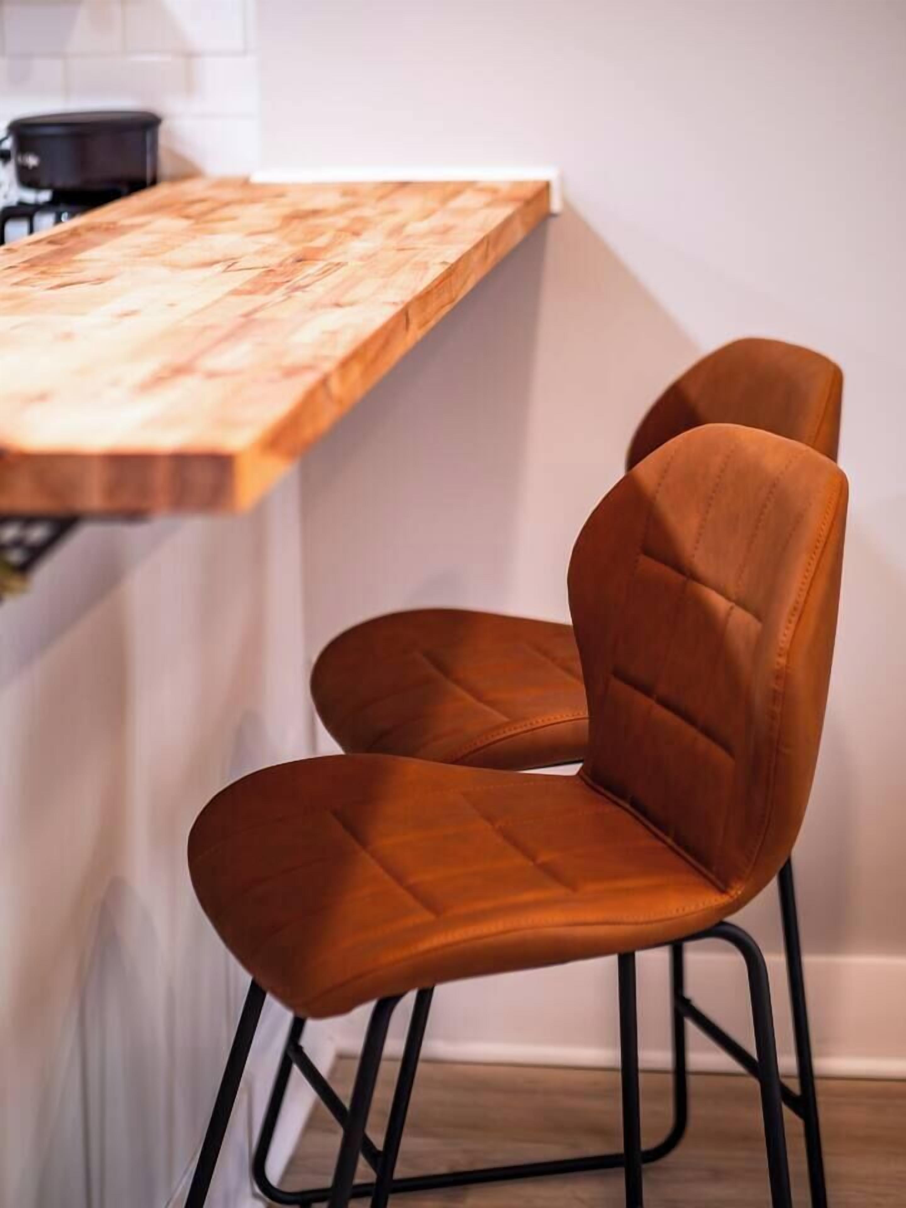 Eine Küche mit einer Holzausziehtafel und zwei braunen Stühlen mit schwarzen Metallbeinen.
