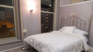Una camera da letto con un letto, una finestra e una lampada a parete.