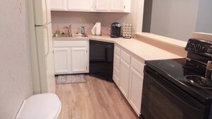 Una cucina compatta con mobili bianchi, un piano cottura nero e una lavastoviglie.
