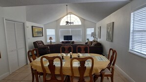 A dining area with a round table, chairs, and a ceiling fan.