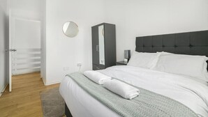 Un dormitorio con cama, armario, espejo y puerta.