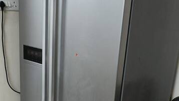A stainless steel LG refrigerator in a kitchen with a tiled floor and a pink wall.