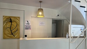A reception desk with a modern pendant light, a sign prohibiting smoking, and a water dispenser. - Black Suites Pinamar  (Pinamar)