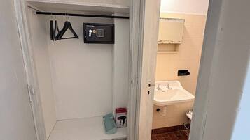 A small, enclosed bathroom with a toilet, sink, and a towel rack.